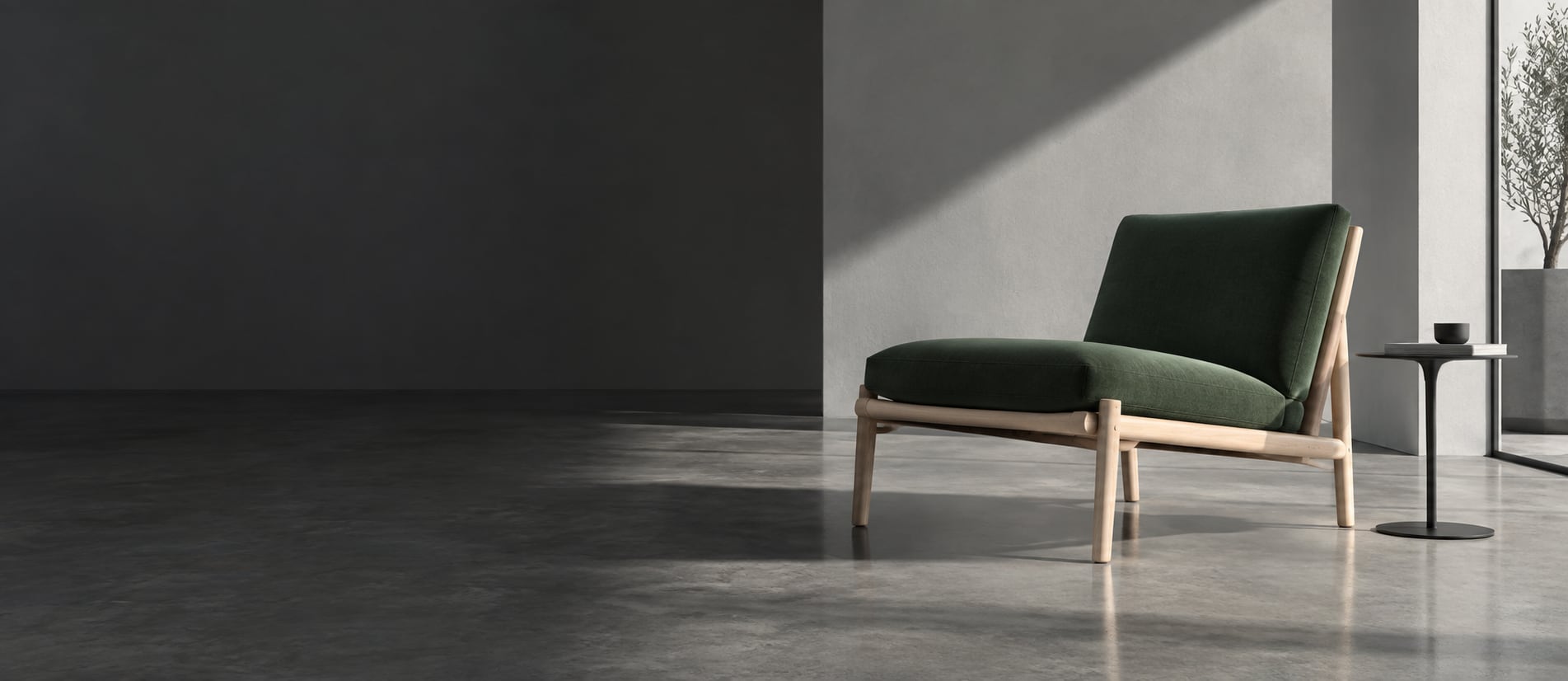 A deep green lounge chair and minimal side table in a gray studio