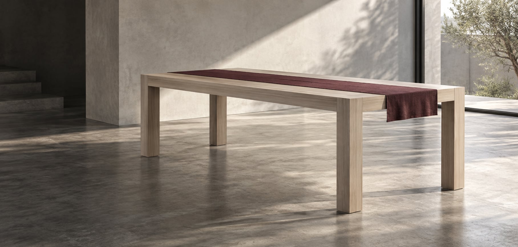 A pale, clean-lined dining table in a gray studio